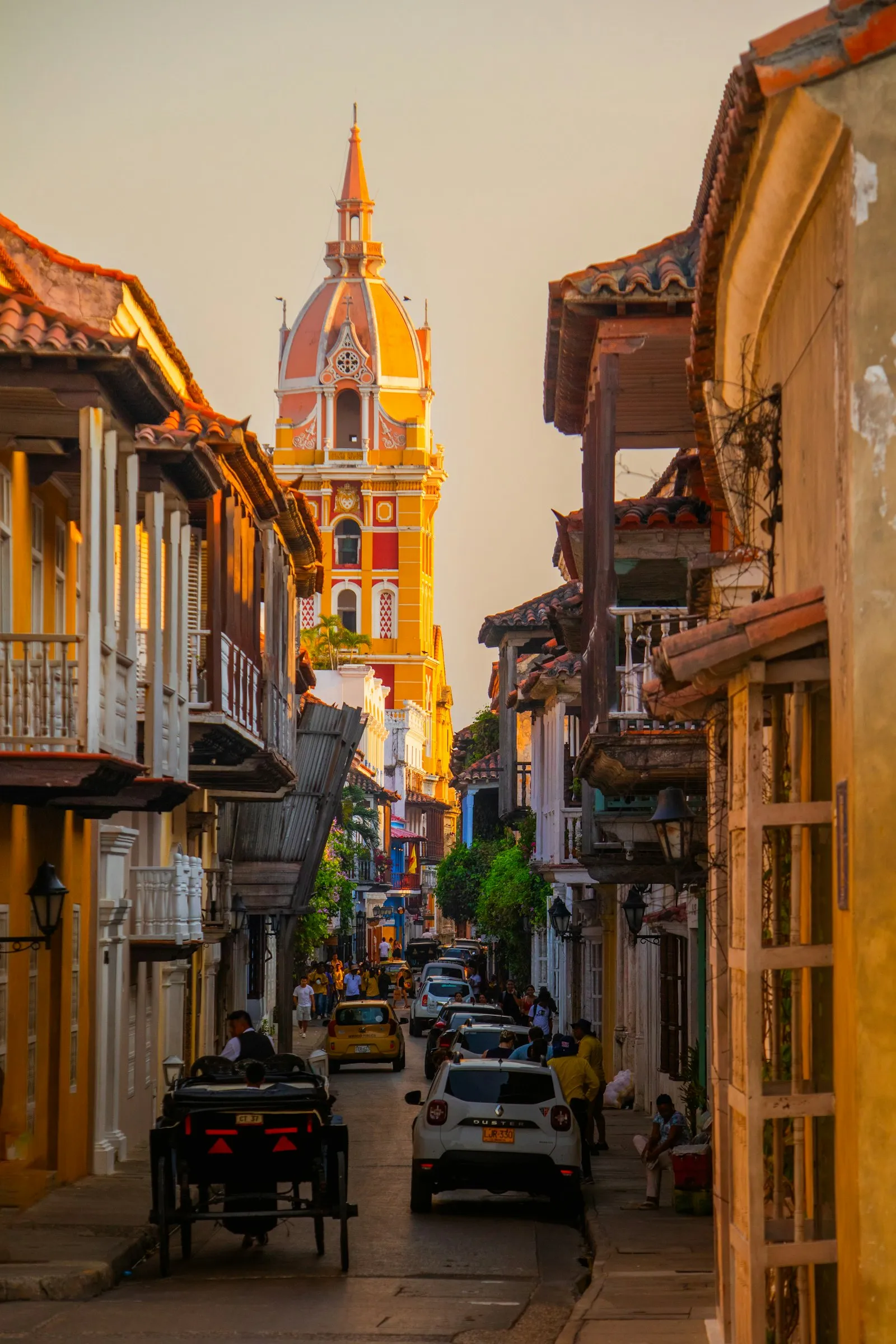 A Cartagena street glowing gold in the evening light, church tower in the distance